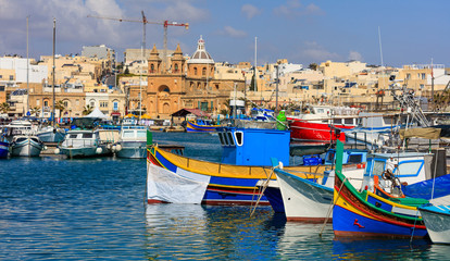 Fototapeta na wymiar Marsaxlokk fishermen village in Malta. Traditional colorful boats at the port of Marsaxlokk