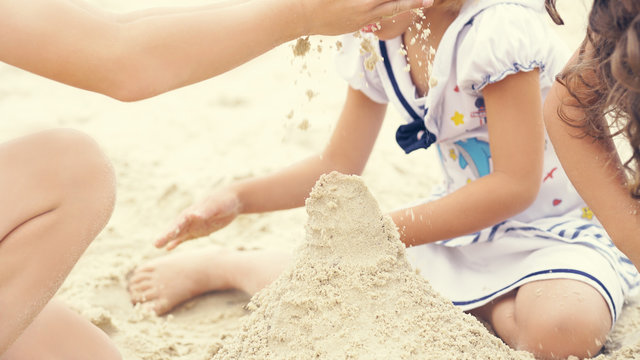 Group of little children build a sand tower, hands closeup