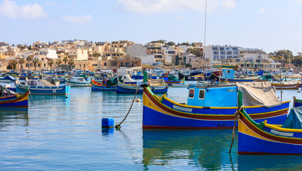 Fototapeta na wymiar Marsaxlokk fishermen village in Malta. Traditional colorful boats at the port of Marsaxlokk