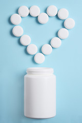 Symbol of the heart with pills  pouring out from a white plastic jar.
