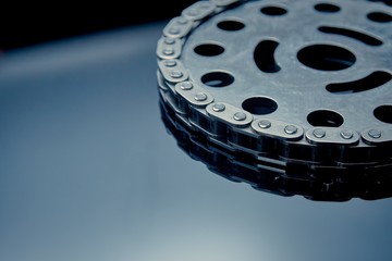 Roller chain with sprocket on dark background. It is used on cars, motorcycles, bicycles and in mechanical engineering.