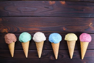 Various ice cream cones on wooden table, flat lay