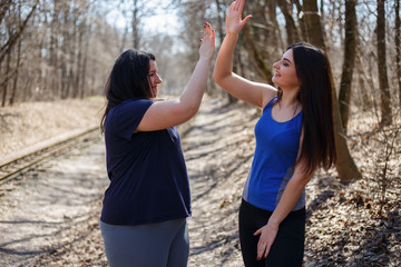 Two happy women friends give a five after jogging