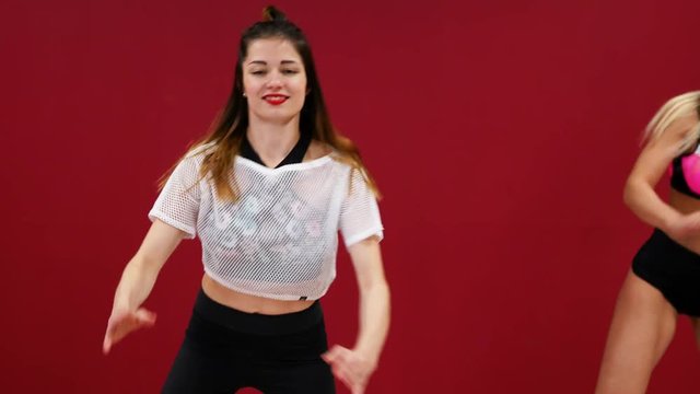 Beautiful sexy girl on a red background with a wall perform fitness exercises on shoes with a spring. Cardio training in the jump style. Jumping without stopping. Burning fat and sternafia figure with