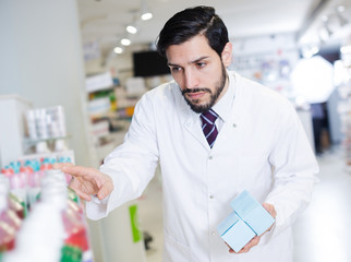 pharmacist standing with medicine on his work place