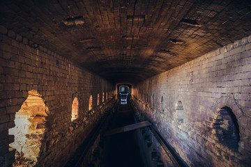 Obraz premium Red brick abandoned underground sewer tunnel with dramatic mysterious atmosphere, inside sewerage