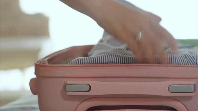 Female hands packing suitcase with clothes, 4k