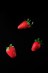 A falling strawberry on a black background.