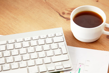 Desk with laptop, eye glasses, earphone, pen and a cup of coffee