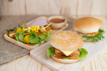 Selective focus of two hamburgers and salad on wood table. Fast food.