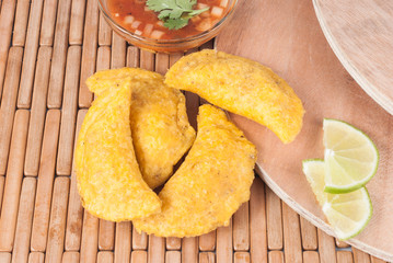 Colombian empanada with spicy sauce on wooden background