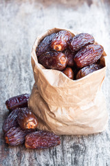 Dried  dates in paper bag on wooden table