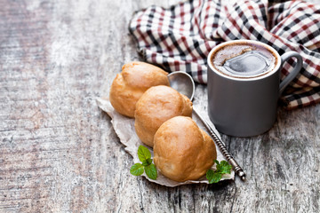 Homemade  profiteroles and cup of coffee on wooden table