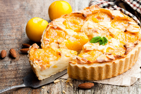 Delicious  tart with yellow plum and almonds on wooden table
