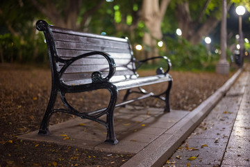 A vacant park bench in Hyde Park, Sydney Australia at night