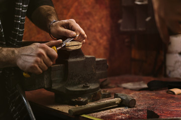 Man works in carpentry workshop. He cuts off excess wood with knife with an ax.