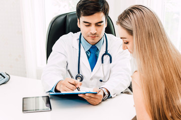 Doctor consulting and check up information with female patien on doctors table in hospital.healthcare and medicine