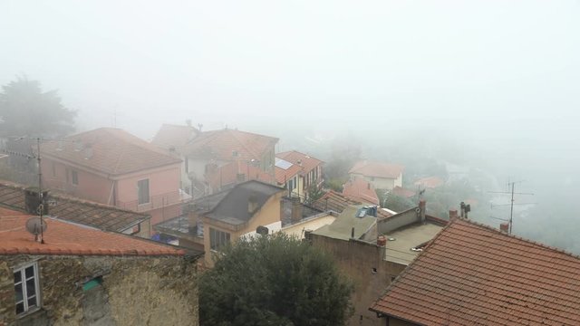 Early foggy morning in the Alpine town. Fog from the mountains makes its way along the medieval streets. Perinaldo, Liguria, Italy.