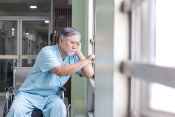 Asian old man sit on wheelchair looking out to other place. People with health care and medical concept.