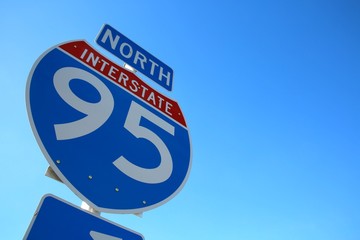 Looking Up at I-95 Sign Backlit by Sun Against Clear Blue Sky