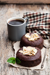 Chocolate  fondant with almonds and cup of coffee on wooden table