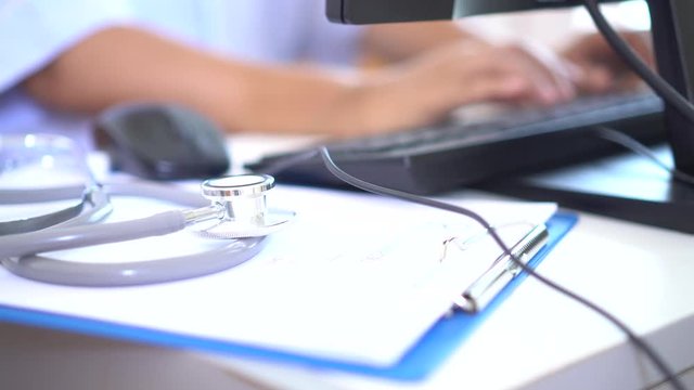 Healthcare and medical concept: Medicine doctor's working and using mouse on laptop computer with Stethoscope on prescription clipboard on workplace in hospital, Focus on stethoscope
