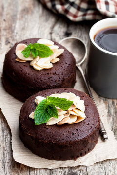 Chocolate  fondant with almonds and cup of coffee on wooden table