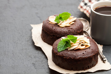 Chocolate  fondant with almonds and cup of coffee on black stone background