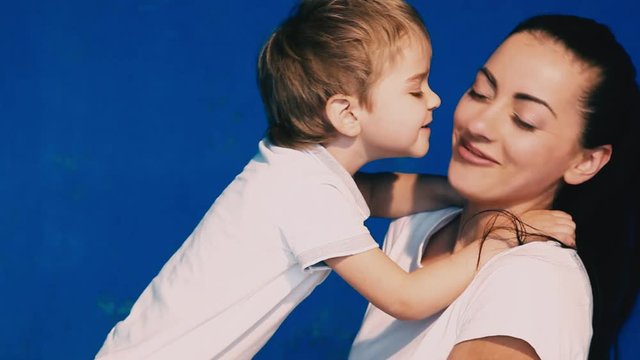 mother and son play laugh and kiss on a blue background