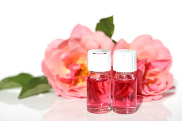 Cosmetics with rose extract.Serum with rose extract for facial skin in glass ampoules and pink roses on a white background.