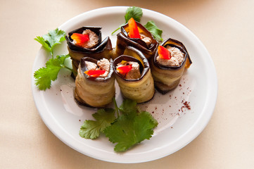 Roll with eggplant stuffed with sweet pepper and parsley on a crockery plate