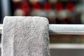 Grey towel hangs on barbell in gym