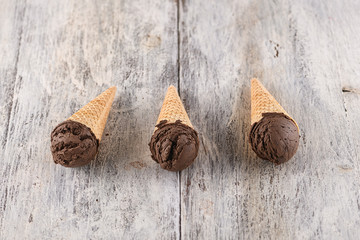 ice cream in waffle cone with utensil on wooden background