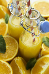 glass bottles with orange and straw on an orange background.