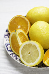 oranges and lemons on a plate on a white background closeup.