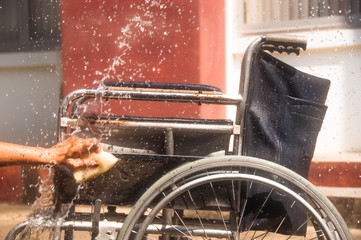 woman cleaning old wheelchair by sponge,asian washing style