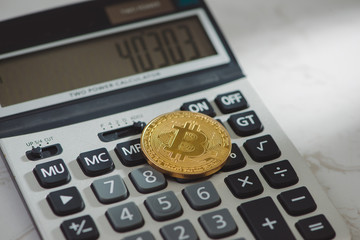 Golden bitcoin with calculator on white background