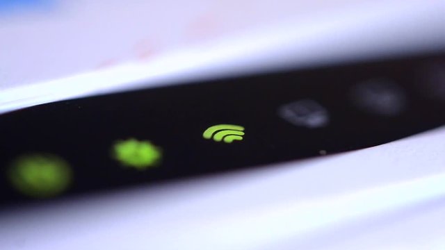 The wifi icon flashes green on the small computer home network router macro. adsl wifi router lights flashing green LED.