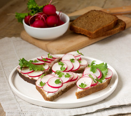 Appetizing sandwiches of rye bread with curd cheese, radishes and lettuce. Rustic style.