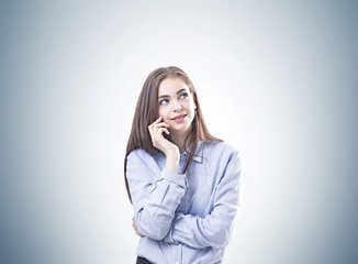 Dreamy young woman in a blue shirt, gray