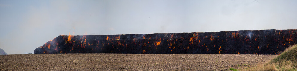 Detail of stack hay in fire on field and sky