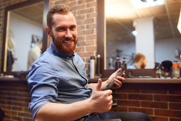 Young handsome bearded man visiting barber shop. Barber concept.