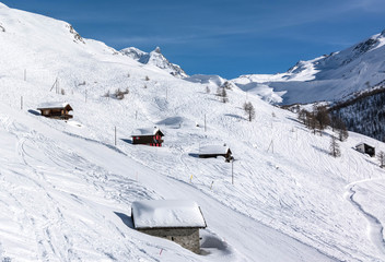 Fototapeta na wymiar Houses on the hillside against the backdrop of mountain peaks. Zermatt Ski Resort Switzerland