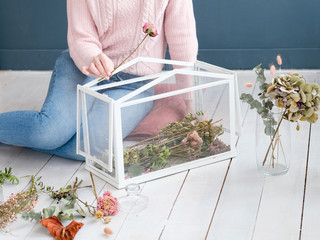 hobby and leisure concept. woman ccreating a unique flower arrangement in a glass box to decorate her home