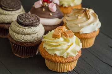 Decorated cup cakes on black table - selective focus