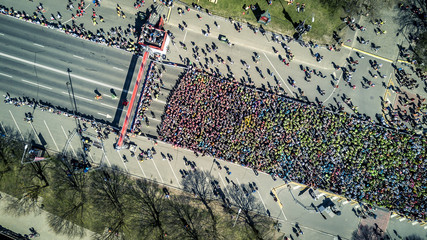 Aerial view from drone on crowd of people who is starting their run on marathon event. Funny shadows on asphalt. - obrazy, fototapety, plakaty