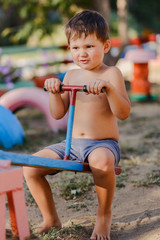 little cute boy without a shirt plays on the Playground