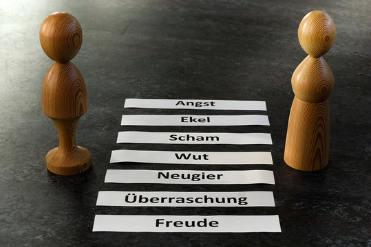 zwei Holzfiguren stehen neben auf Zetteln geschriebenen Emotionen, Darstellung aus der Psychotherapie, Familientherapie