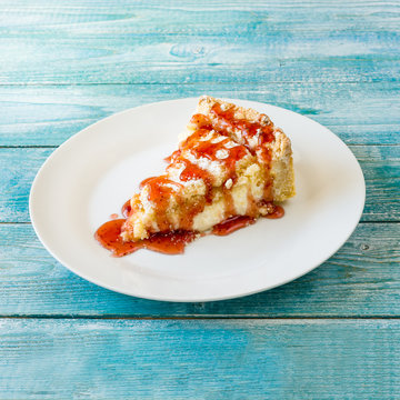 cheesecake in berry syrup on blue wooden background