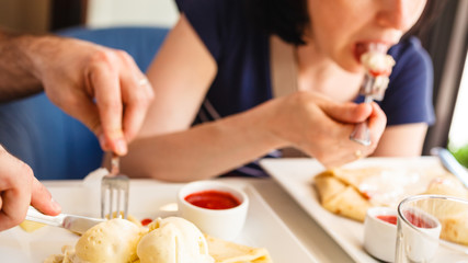 Obraz na płótnie Canvas Eating pancake with ice cream and strawberry sauce